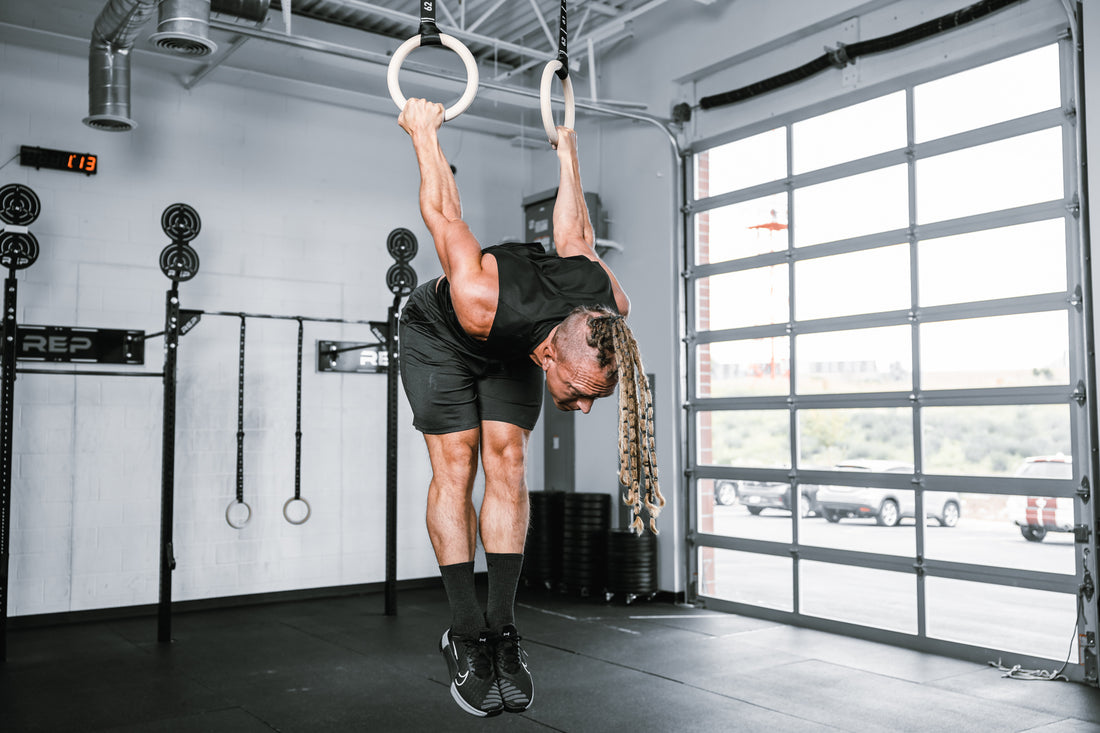 Athlete working out on REP Competition Gymnastic Straps and Wood Rings hanging from metal ceiling infrastructure