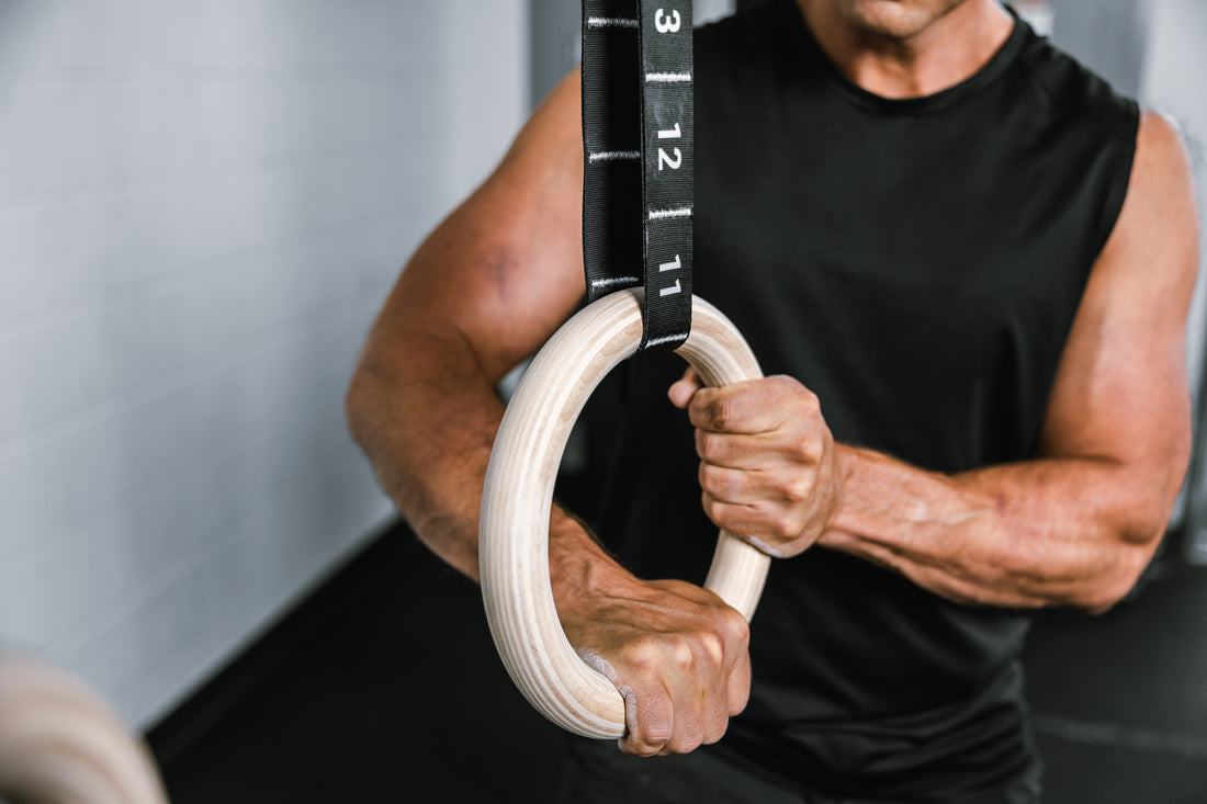 Athlete applying body weight to the REP Competition Gymnastic Straps and Wood Rings to check setup