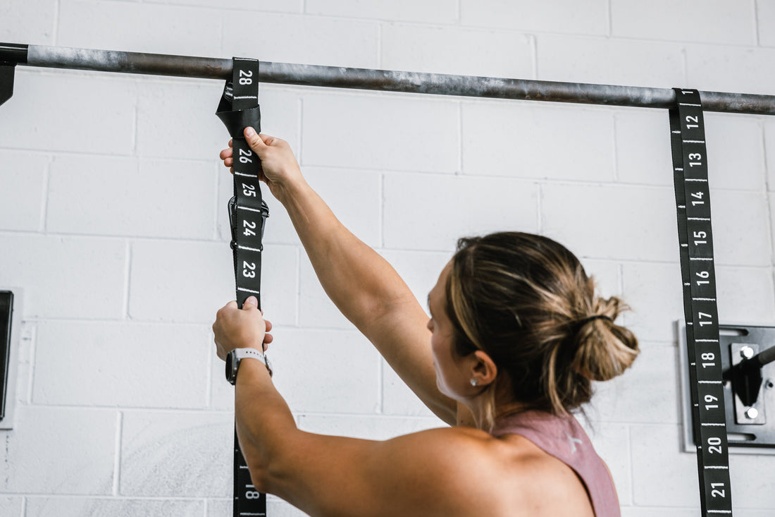 Athlete securing the REP Competition Gymnastic Straps to a REP Wall-mounted Rig