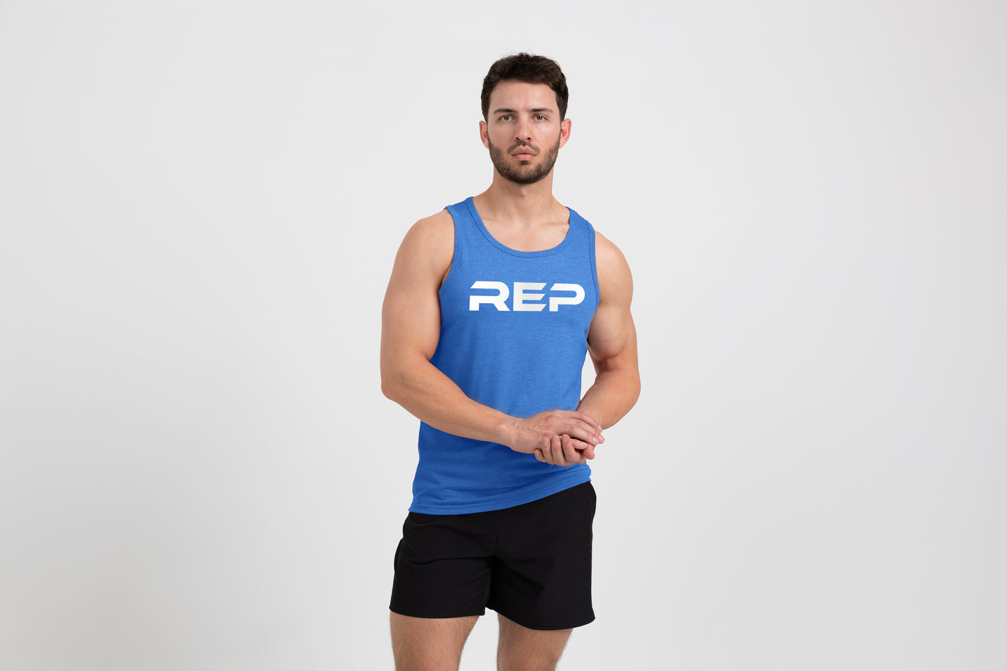 Man wearing the Men's Daily Driver Tri-Blend Tank in Heather Azure/White with shorts