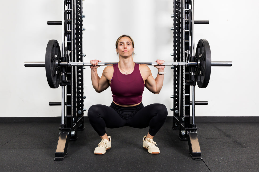 Athlete squatting on the front of a rack mounted Smith Machine