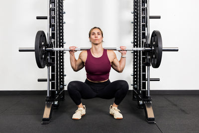 Athlete squatting on the front of a rack mounted Smith Machine