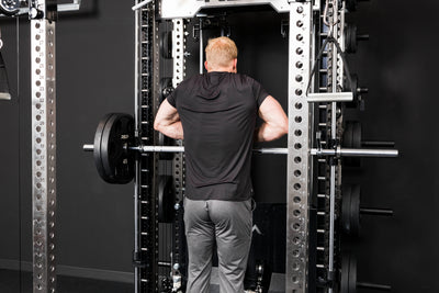 Athlete doing upright rows on the Smith Machine inside a power rack with asymmetrical loading