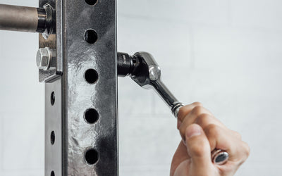 Someone using a ratchet wrench with REP's 24mm Rack Socket to install a bolt on a 4000 Series Power Rack