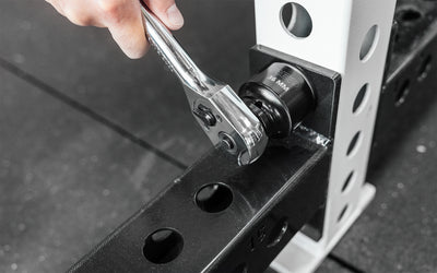 Someone using a ratchet wrench with REP's 36mm Rack Socket to install a bolt on a 5000 Series Power Rack