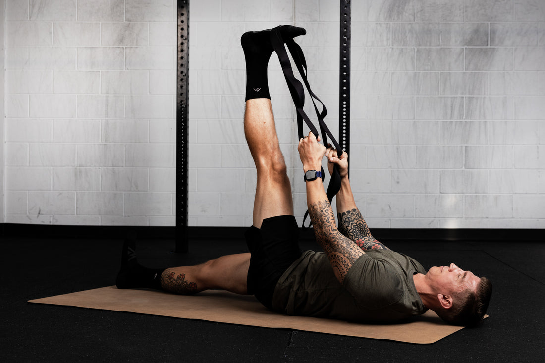 Person exercising using stretching band on a mat in a gym setting