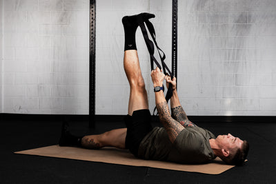 Person exercising using stretching band on a mat in a gym setting