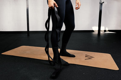 Person holding stretching strap on a mat in a gym setting