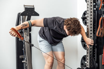 An athlete working out with a REP USA Leather Single Handle Cable Attachment in Brown on a cable machine