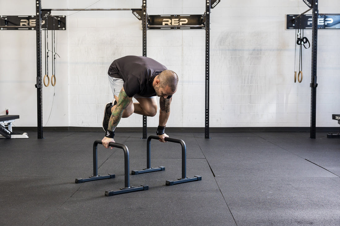 Athlete doing a knee tuck on the REP Fitness Parallette Bars