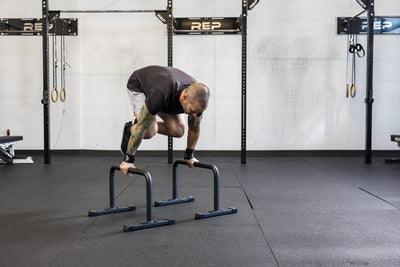 Athlete doing a knee tuck on the REP Fitness Parallette Bars